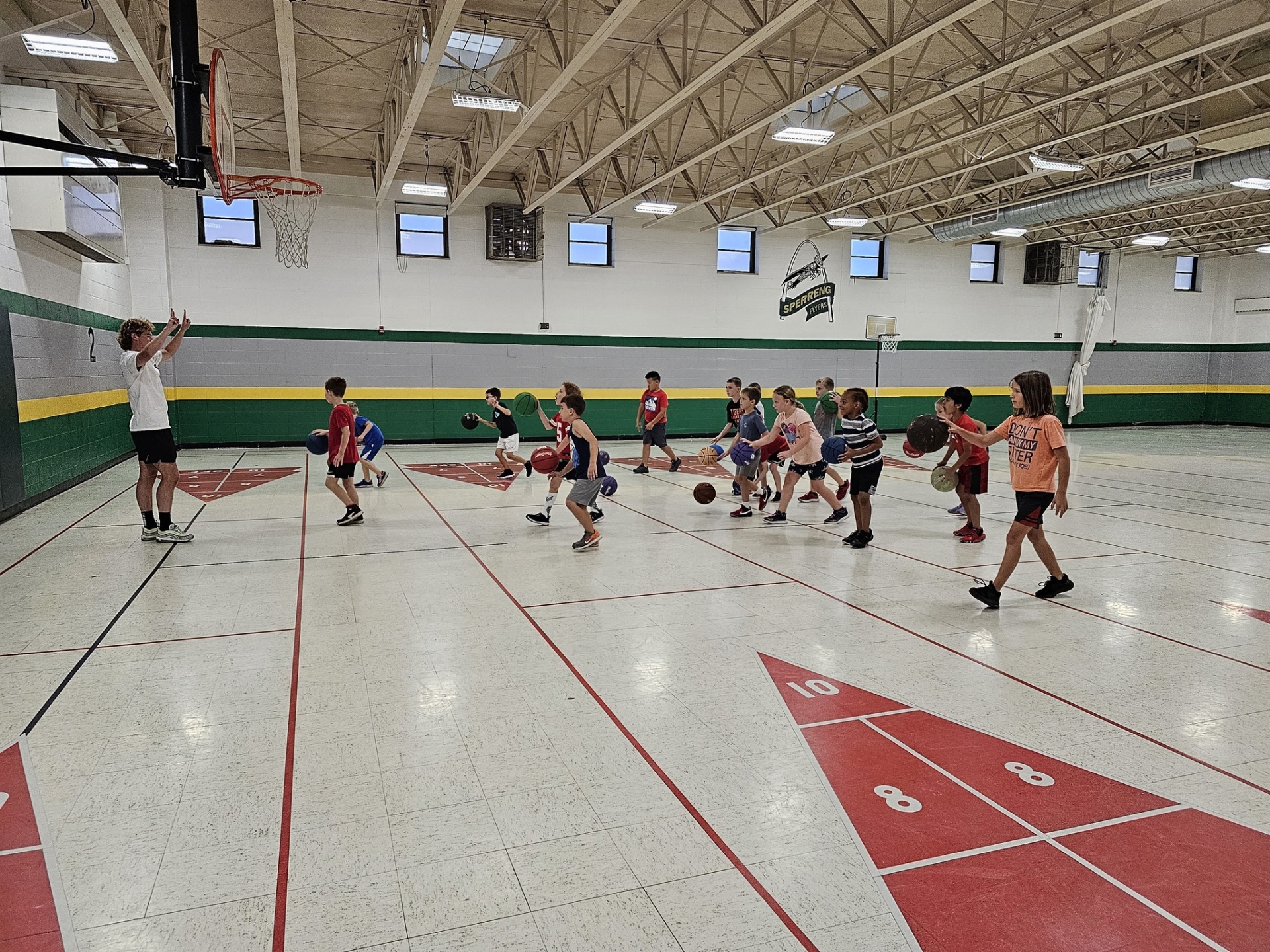 Kids practicing basketball drills in a school gym